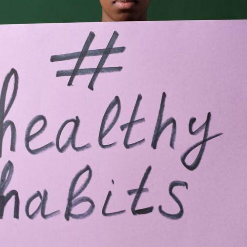 Person holding a "#healthyhabits" sign, emphasizing wellness.