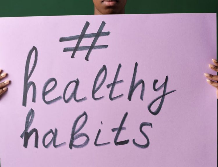 Person holding a "#healthyhabits" sign, emphasizing wellness.