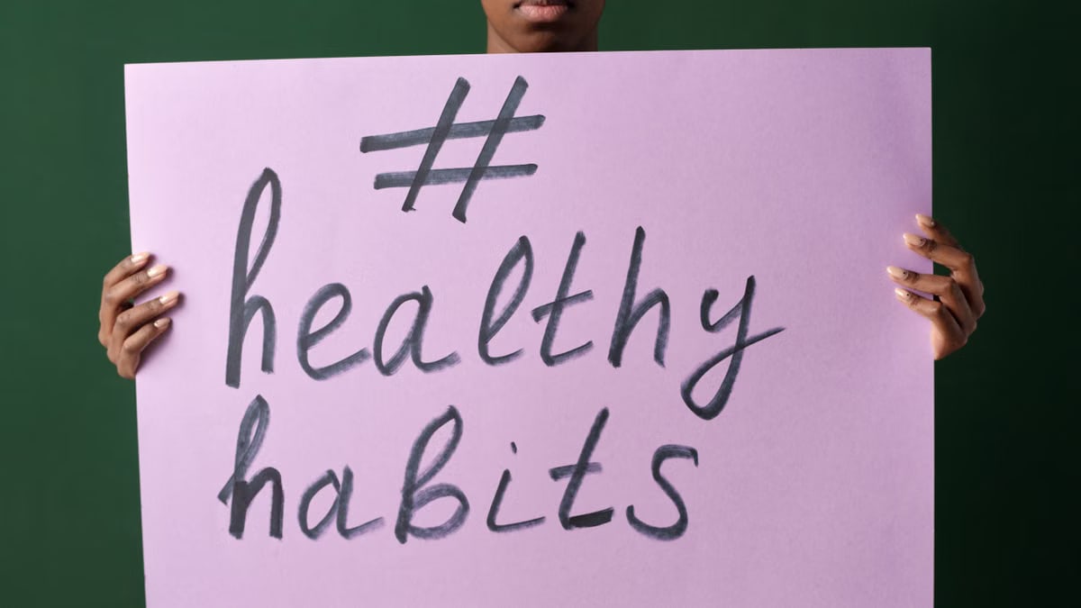 Person holding a "#healthyhabits" sign, emphasizing wellness.